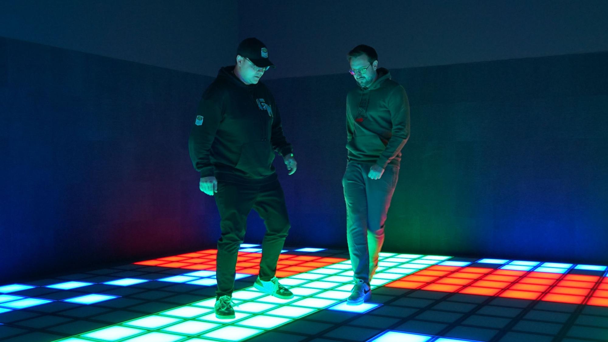 Pierre Pieroth und Paul Nitschke hüpfen auf grünen, roten und blauen LED-Kacheln hin und her.