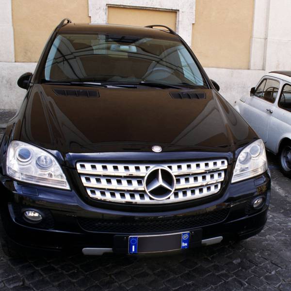 Parkende Autos: Ein großer schwarzer SUV und ein winziger weißer Fiat 500 nebeneinander eingeparkt.