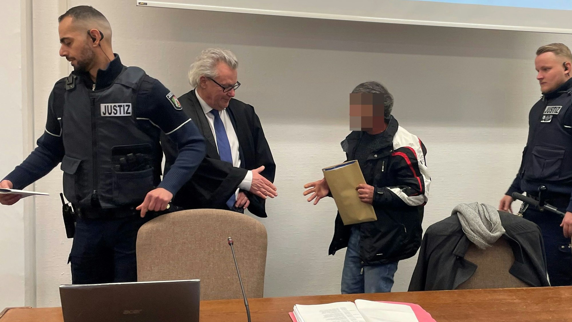 Der Angeklagte im Landgericht mit seinem Verteidiger Gordon Christiansen und zwei Wachtmeistern.