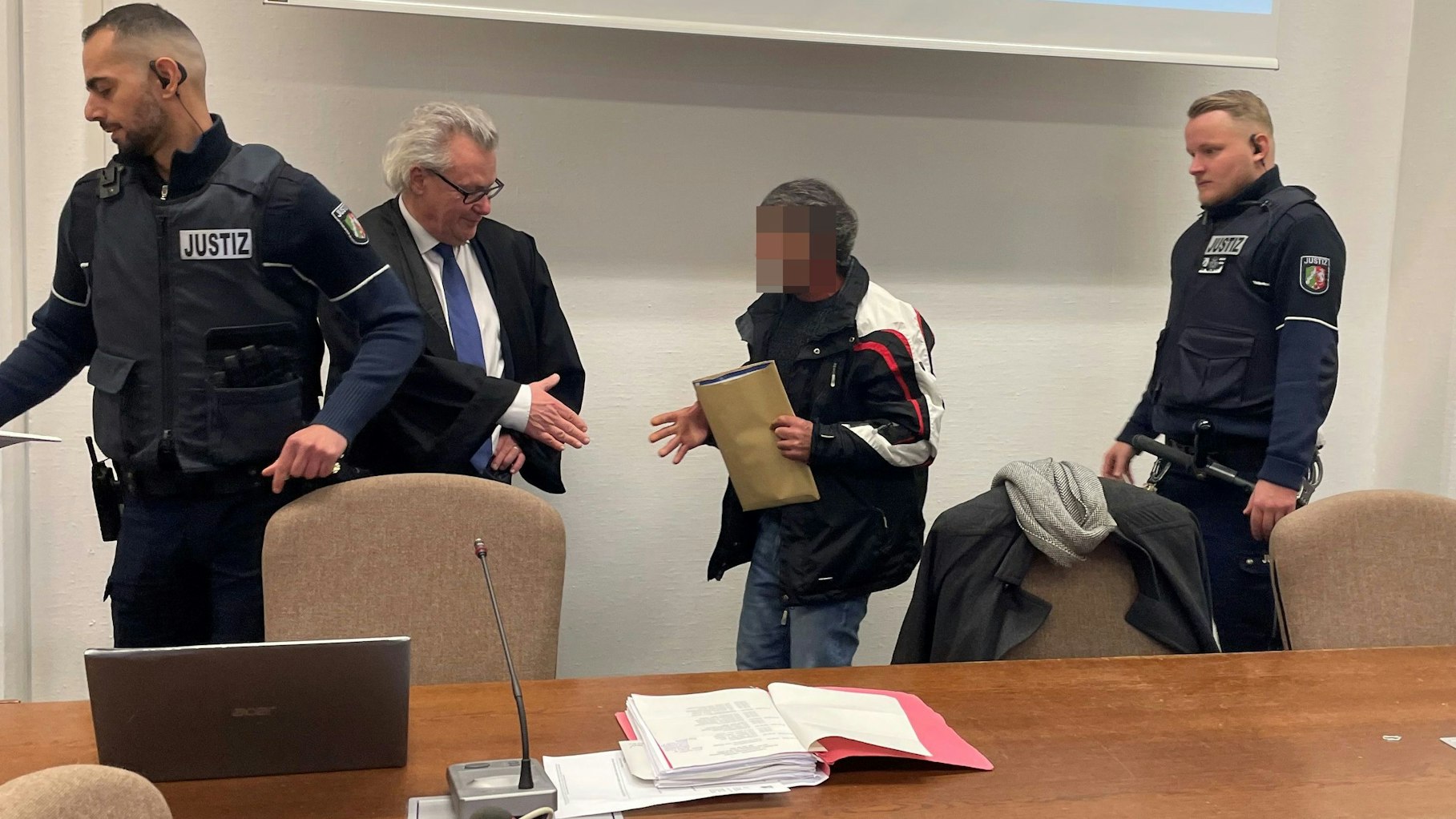 Der Angeklagte im Landgericht mit seinem Verteidiger Gordon Christiansen und zwei Wachtmeistern.