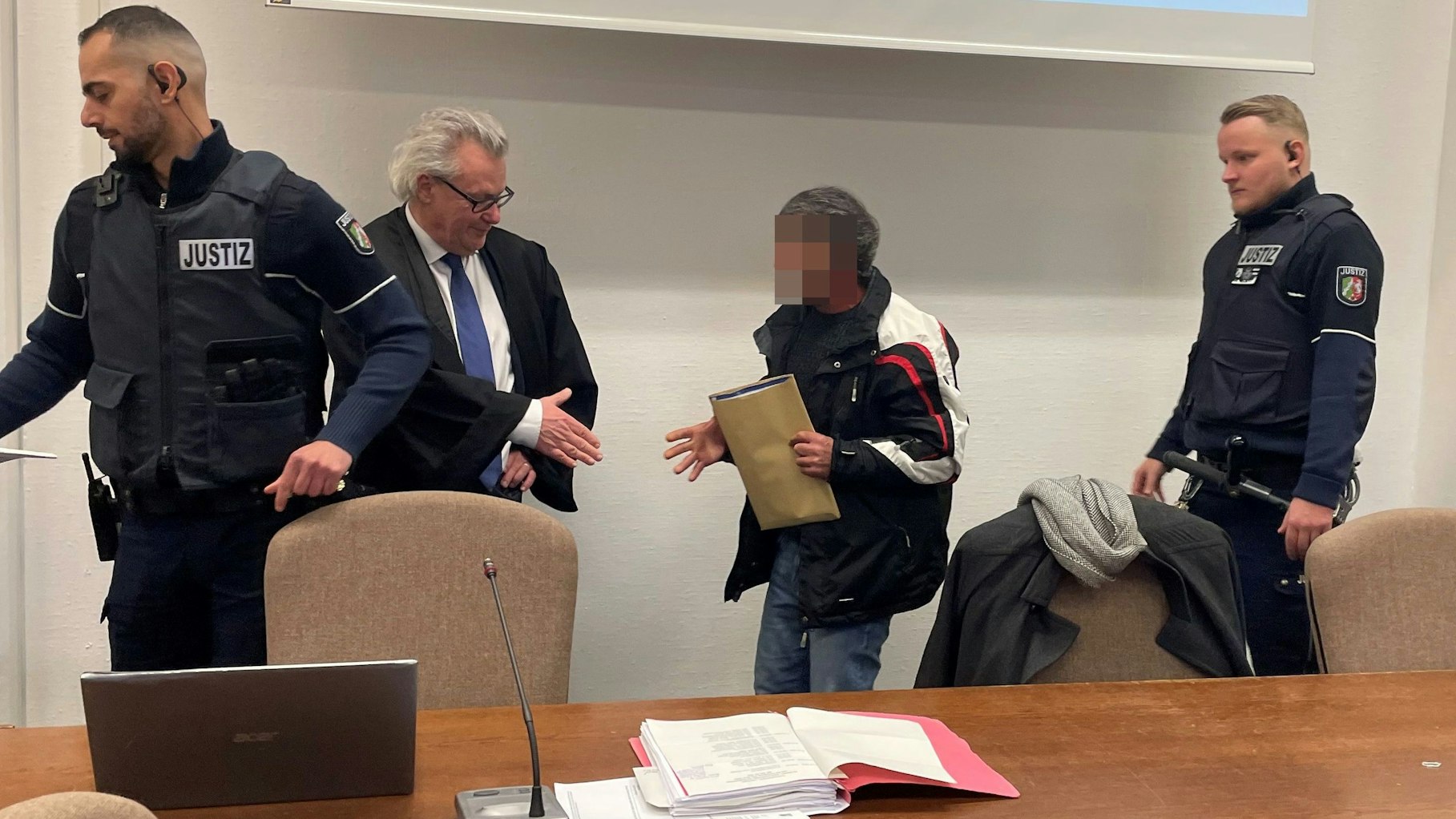 Der Angeklagte im Landgericht mit seinem Verteidiger Gordon Christiansen und zwei Wachtmeistern.