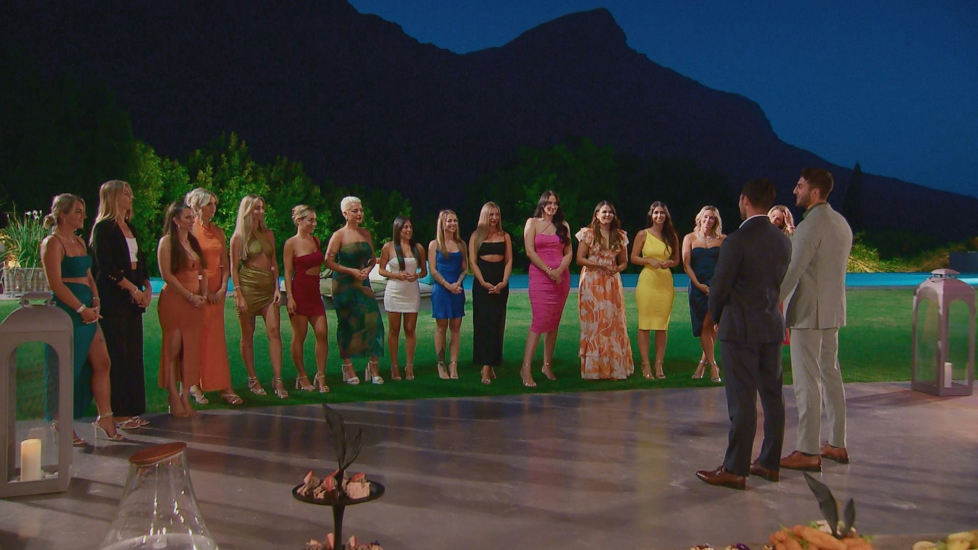 15 Frauen stehen in einem Halbkreis, zwei Männer stehen ihnen gegenüber.