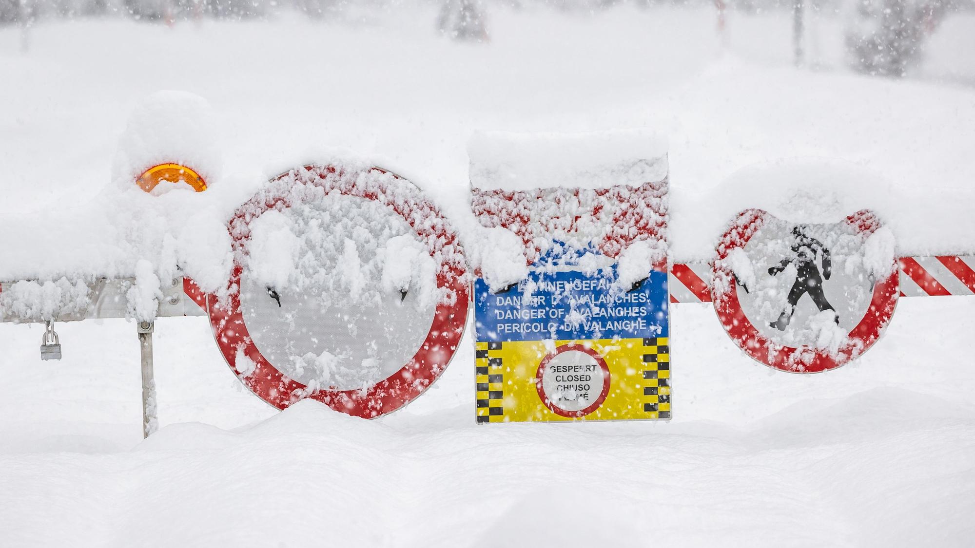 Eine Straßensperre mit mehreren Warnschildern blockiert eine Straße in den Alpen. Starker Schneefall kommt am Wochenende auf Österreich, die Schweiz und Italien zu. (Symbolbild)