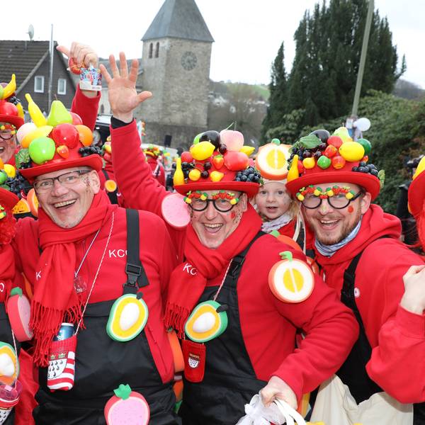 Menschen mit Obst auf den Hüten Stehen vor der Kürtener Kirche St. Johannes Baptist.