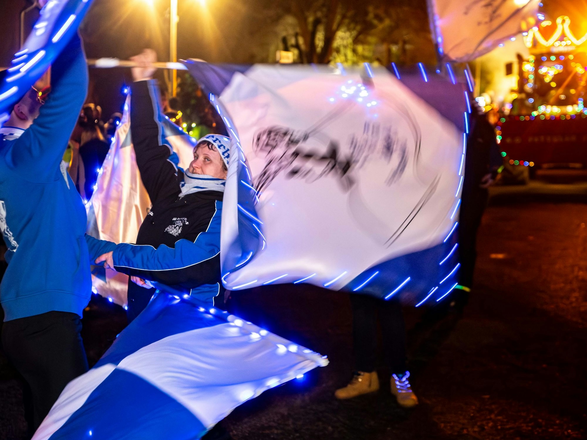 Zwei Fahnenschwenker der KG Alt Oeskerche sind mit ihren mit Lichtern geschmückten Fahnen in Aktion.
