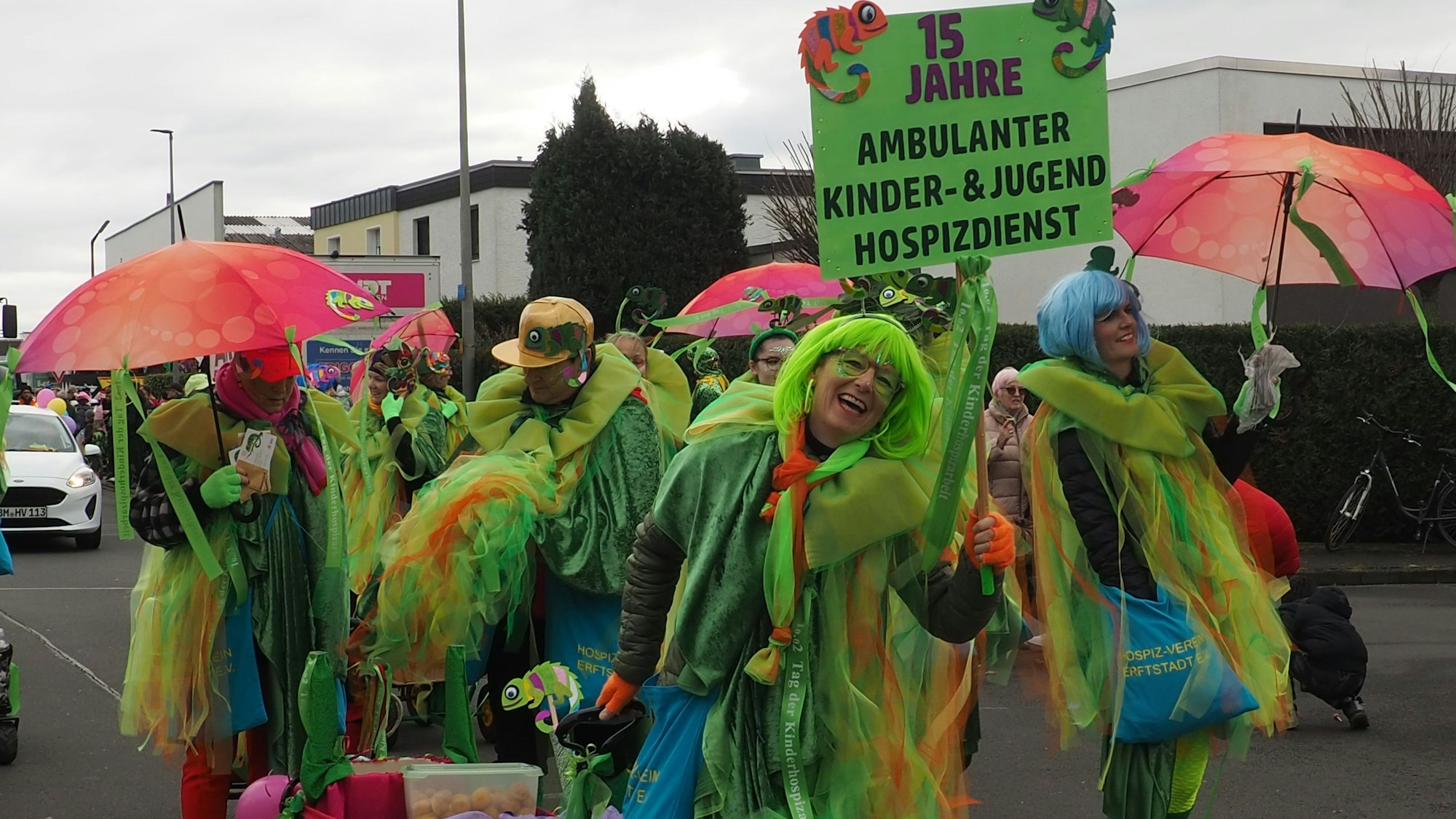 Menschen in bunten Kostümen sind mit einem Handwagen unterwegs.