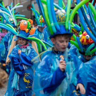 Kinder in bunten Kostümen werfen Kamelle.