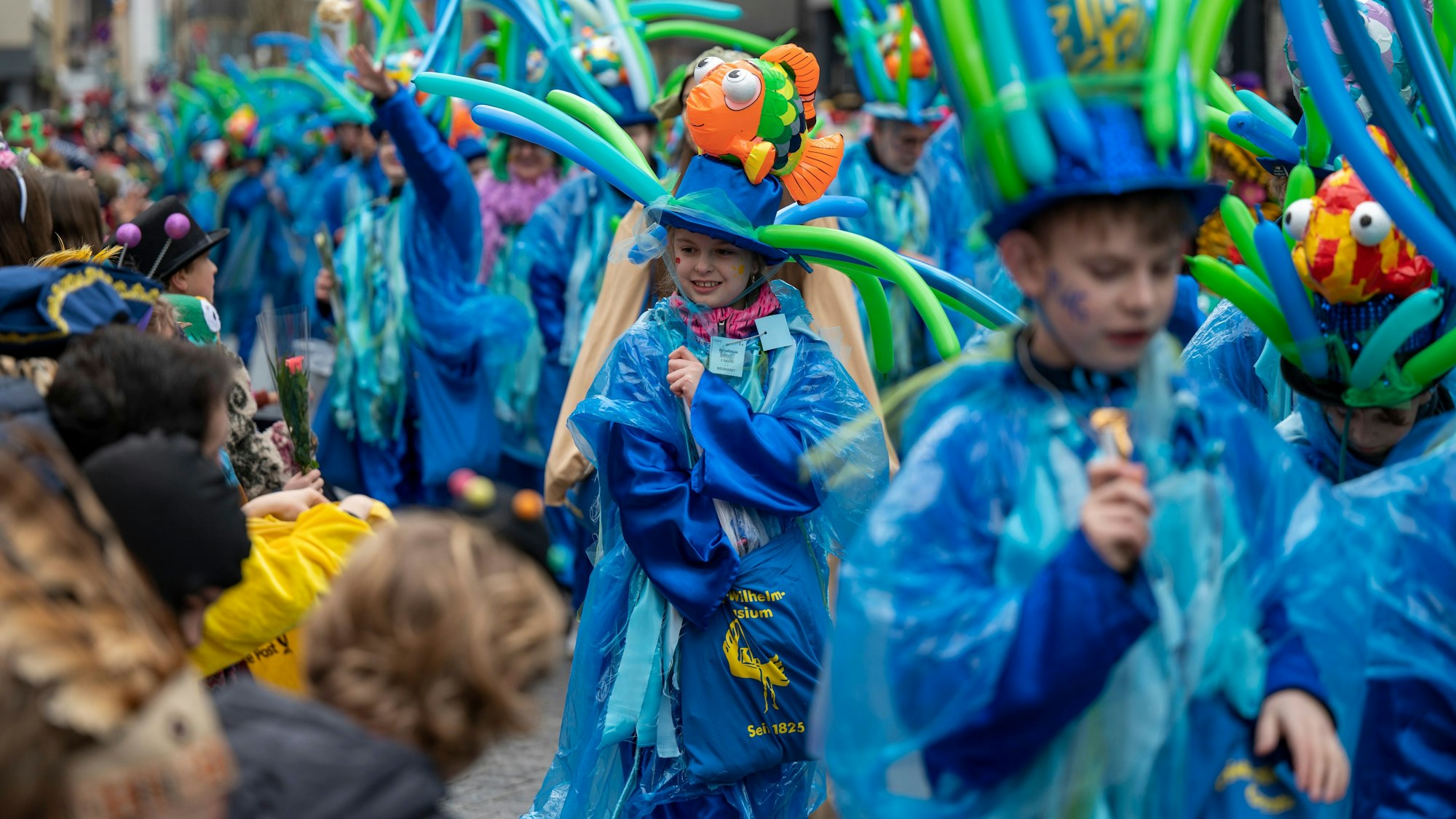 Kinder in bunten Kostümen werfen Kamelle.