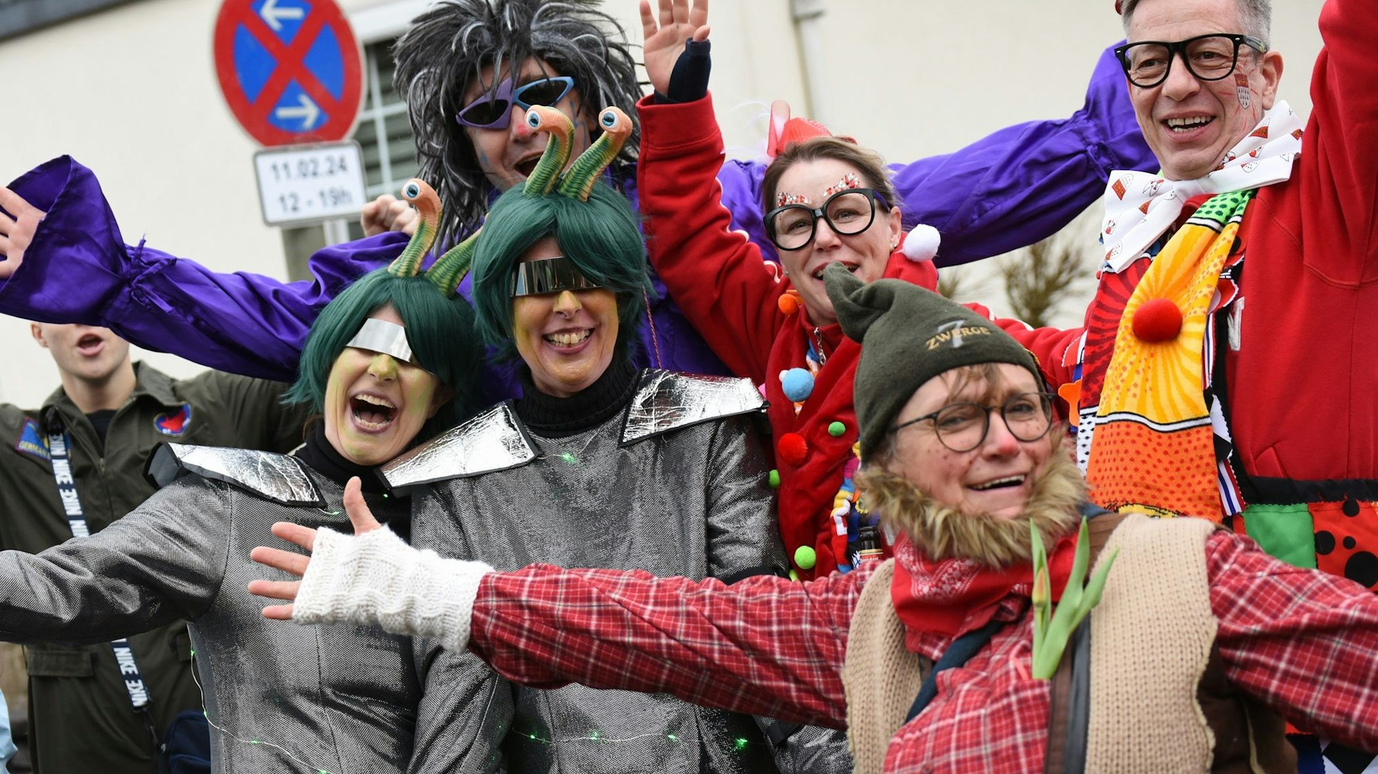 Verkleidete Leute an einem Zugweg jubeln in die Kamera.