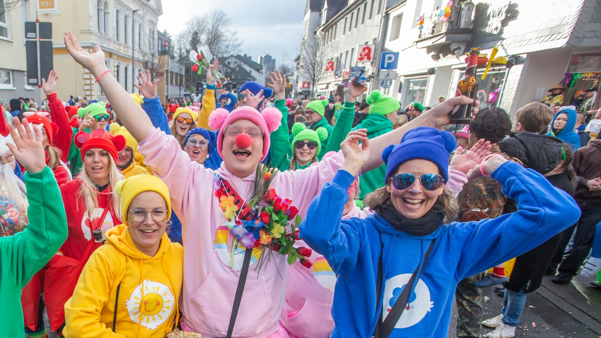 Eine Gruppe in einem Karnevalszug ist als bunte Glücksbären verkleidet.