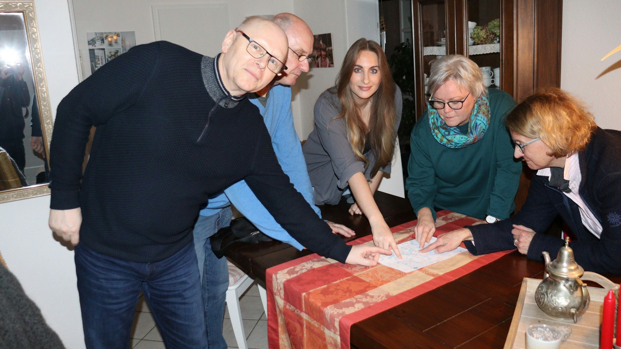 Männer und Frauen stehen um einen Tisch und zeigen auf verschiedene Punkte auf einer Karte.