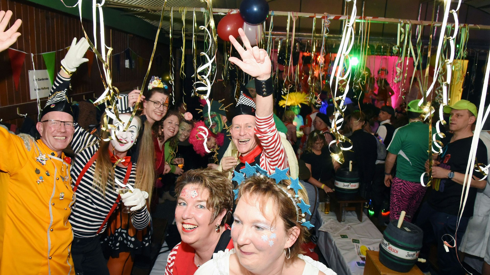 Kostümierte feiern in einer Halle auf einer Karnevalsparty.