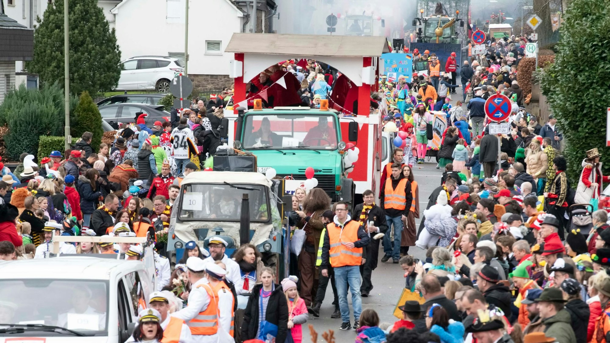 Ein Karnevalszug schlängelt sich durch eine mit Jecken voll besetzte Straße.