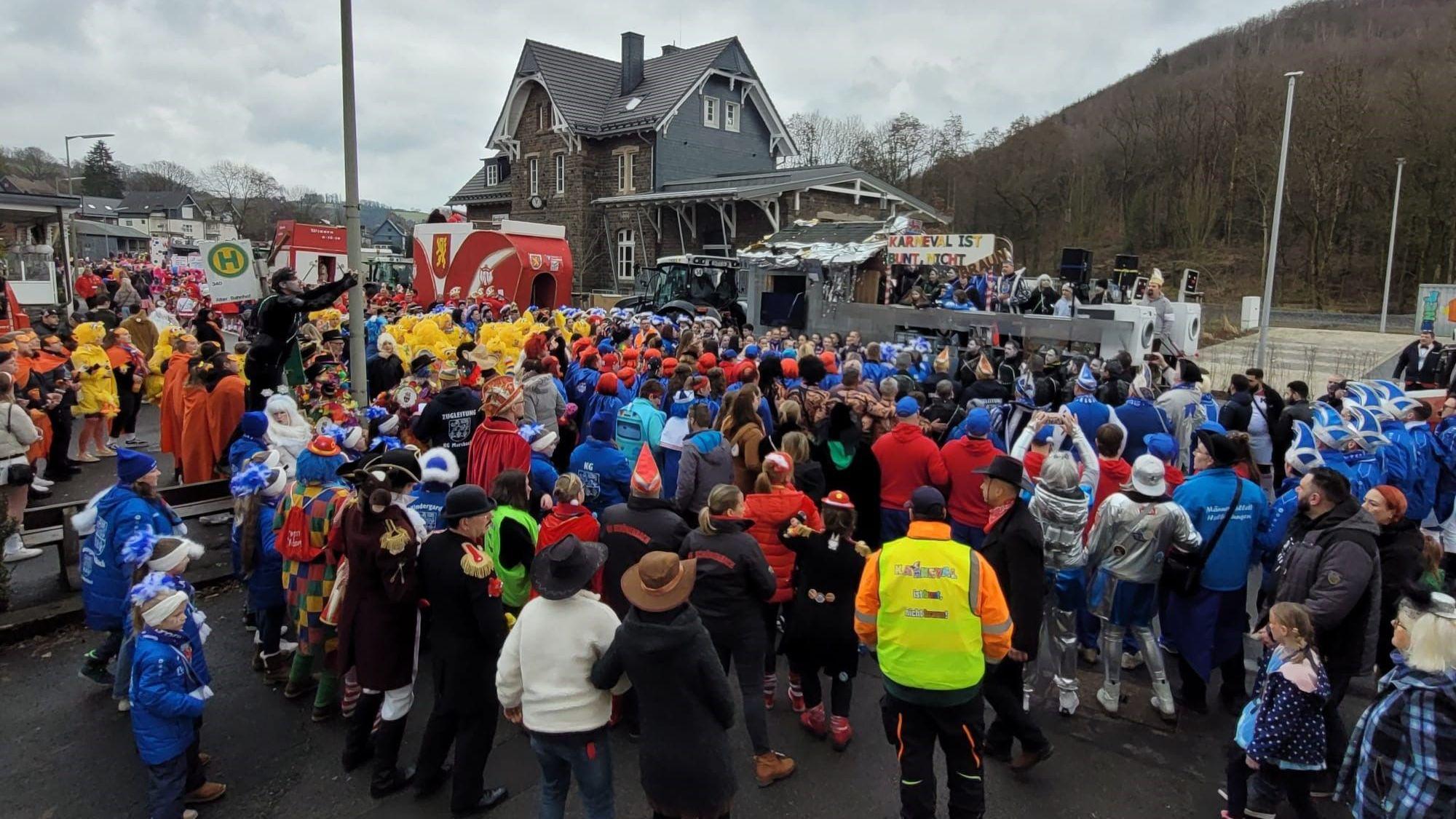 Zahlreiche Menschen stehen vor dem Prinzenwagen in Morsbach beisammen. Auf diesem ist ein Schild zu sehen, auf dem steht: „Karneval ist bunt, nicht braun“.