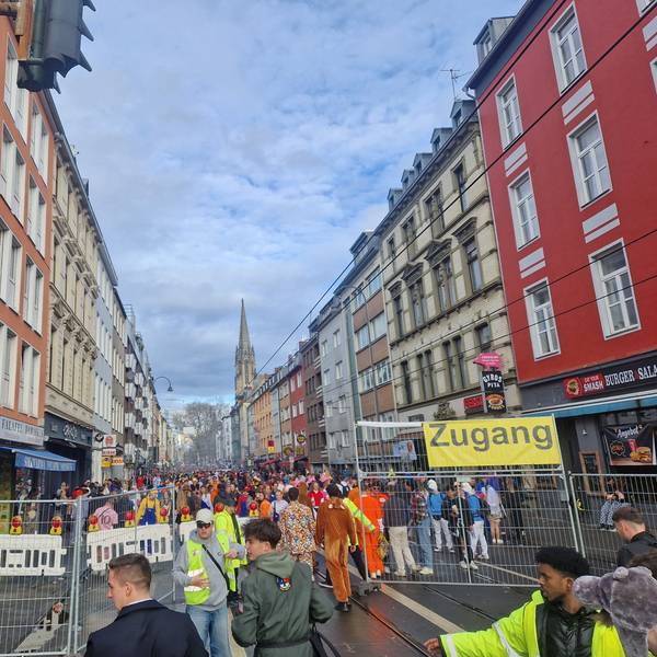 Verkleidete Menschen stehen auf der eingezäunten Zülpicher Straße.