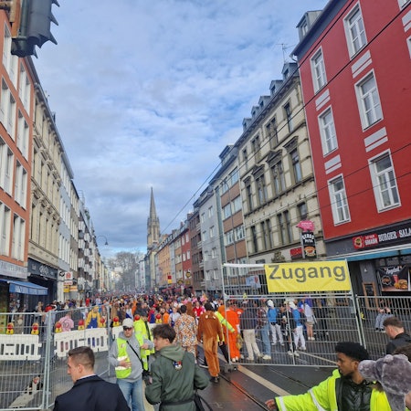 Verkleidete Menschen stehen auf der eingezäunten Zülpicher Straße.