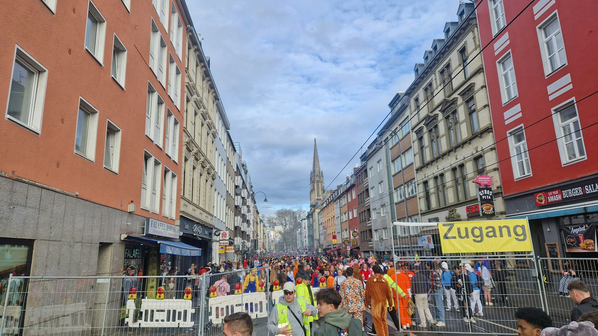 Verkleidete Menschen stehen auf der eingezäunten Zülpicher Straße.