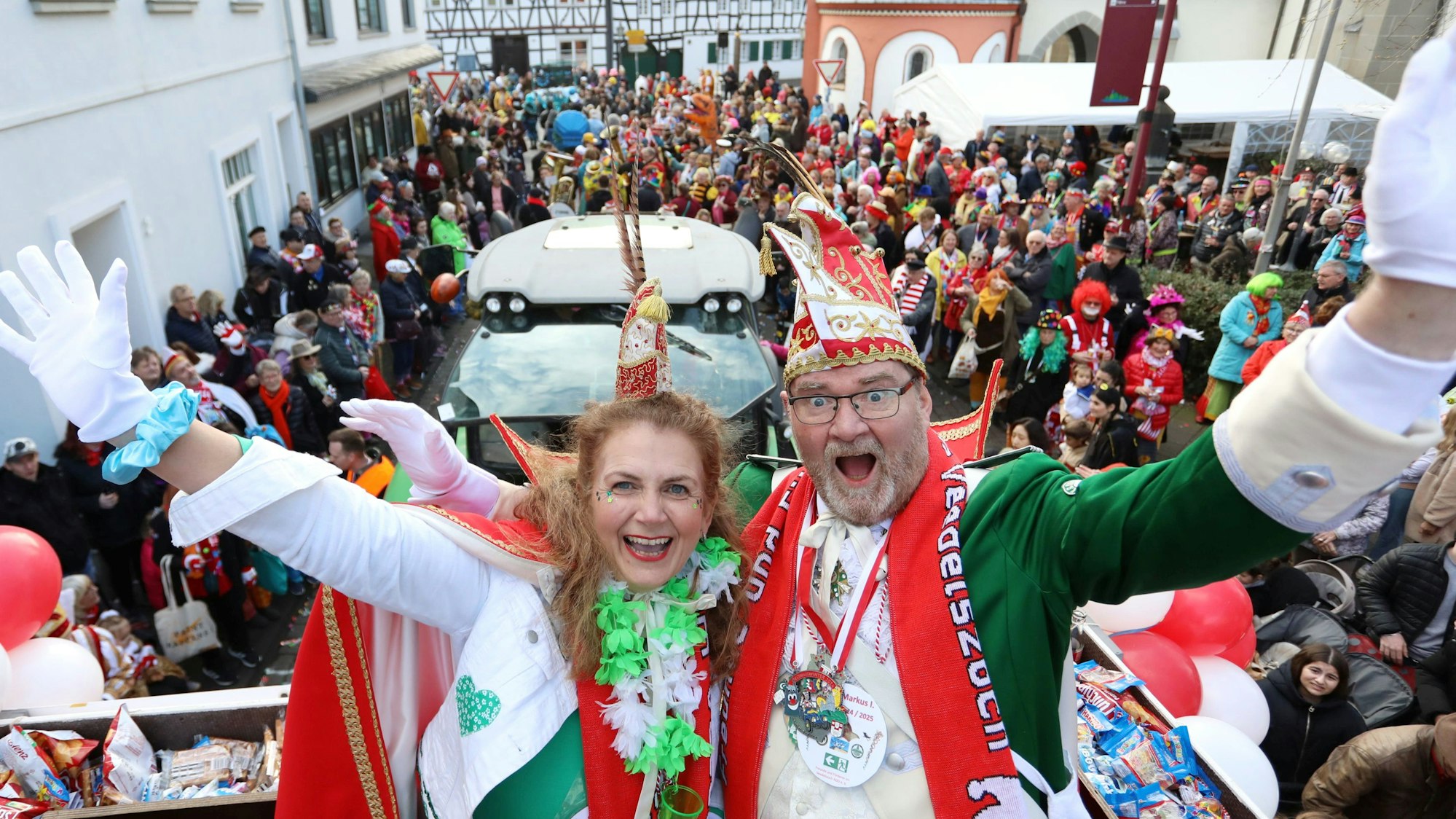 Das neue Prinzenpaar hoch oben auf dem Prinzenwagen, im Hintergrund zahlreiche kostümierte Jecken auf der Straße.