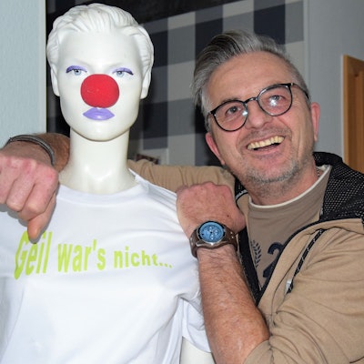 Auf dem Foto ist Ingo Stromberg zu sehen. Er lehnt sich an eine Schaufensterpuppe an, die eine rote Pappnase trägt.