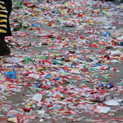 Buntes Konfetti und Bonbons liegen zertreten auf dem Weg.