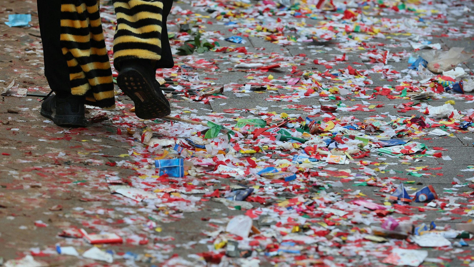 Buntes Konfetti und Bonbons liegen zertreten auf dem Weg.