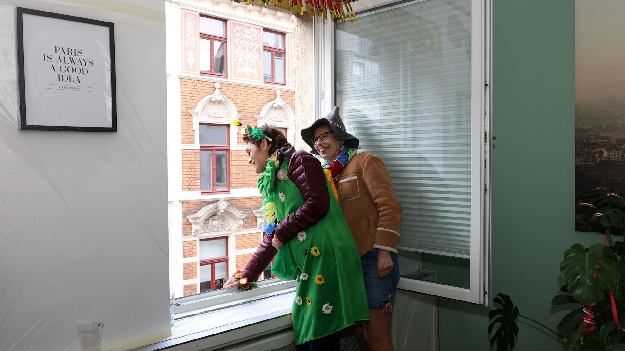 Die Französinnen Beatrice und Christine schauen den Rosenmontagszug aus dem Wohnzimmerfenster. Der Frankreich-Bezug der Familie ist in der Wohnung überall zu sehen.