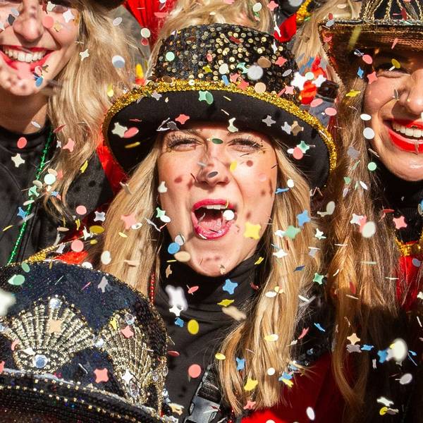 Drei verkleidete Frauen in buntem Konfettiregen.