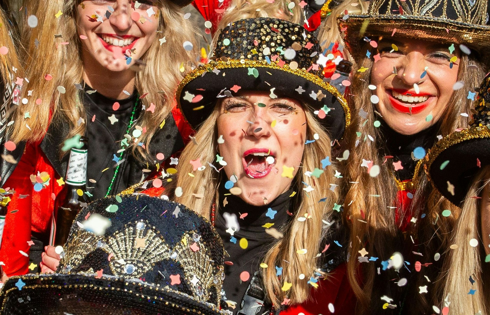 Mehrere kostümierte Damen im Konfettiregen.