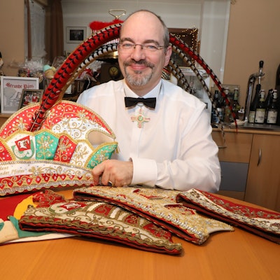 Der Präsident der Großen Gladbacher KG, Alexander Pfister, sitzt an einem Tisch mit seiner neuen Präsidentenkappe zum elfjährigen Amtsjubiläum. Auf dem Tisch: weitere Kappen teils aus den 20er Jahren (l.) und von seinem Vor-Vorgänger Franz Heinrich Krey