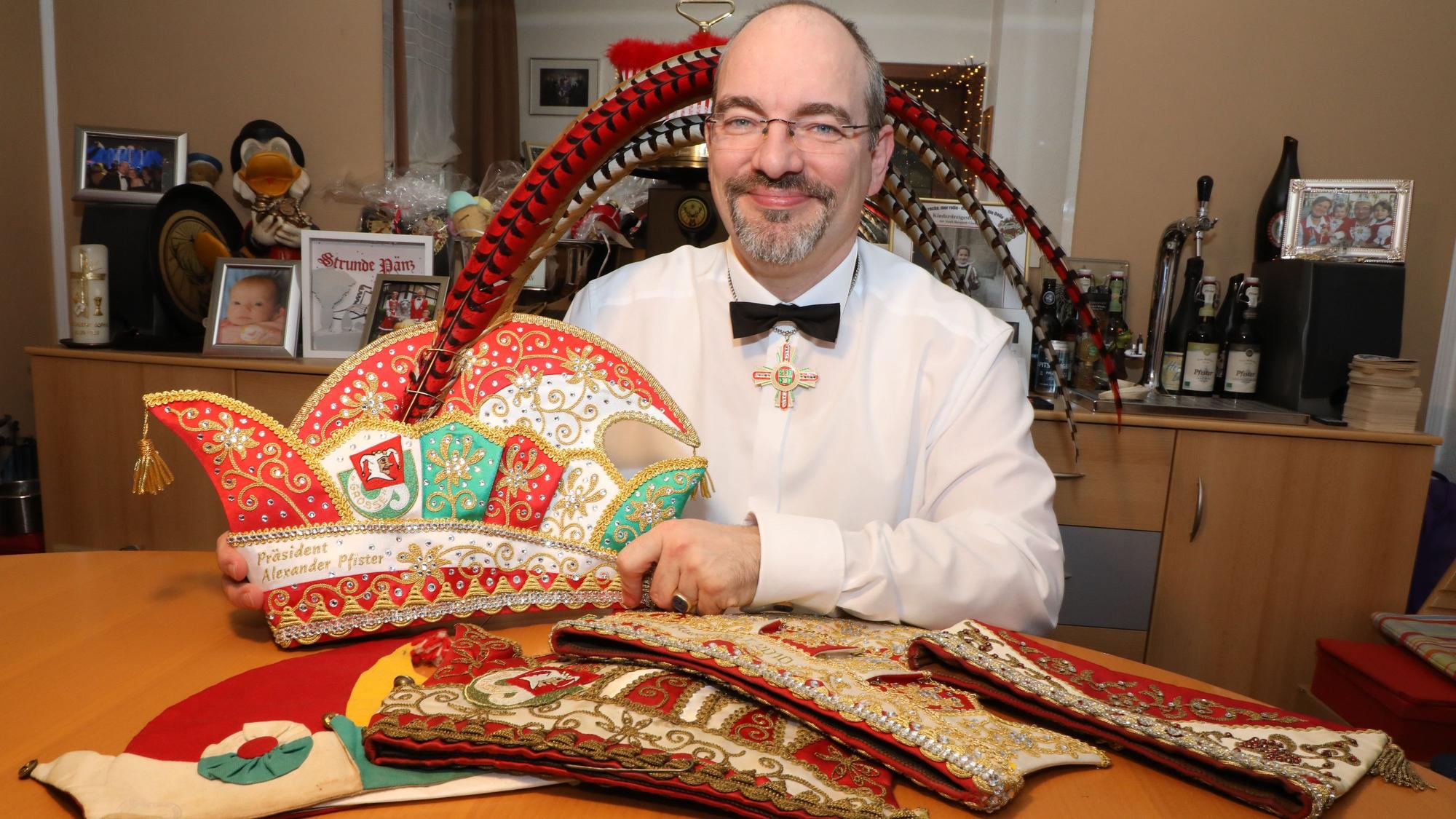 Der Präsident der Großen Gladbacher KG, Alexander Pfister, sitzt an einem Tisch mit seiner neuen Präsidentenkappe zum elfjährigen Amtsjubiläum. Auf dem Tisch: weitere Kappen teils aus den 20er Jahren (l.) und von seinem Vor-Vorgänger Franz Heinrich Krey