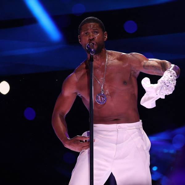 Usher auf der Bühne im Allegiant-Stadion während der Halbzeit-Show des 58. Super Bowls. Er singt ins Standmikrofon, zieht dabei sein weißes T-Shirt aus.