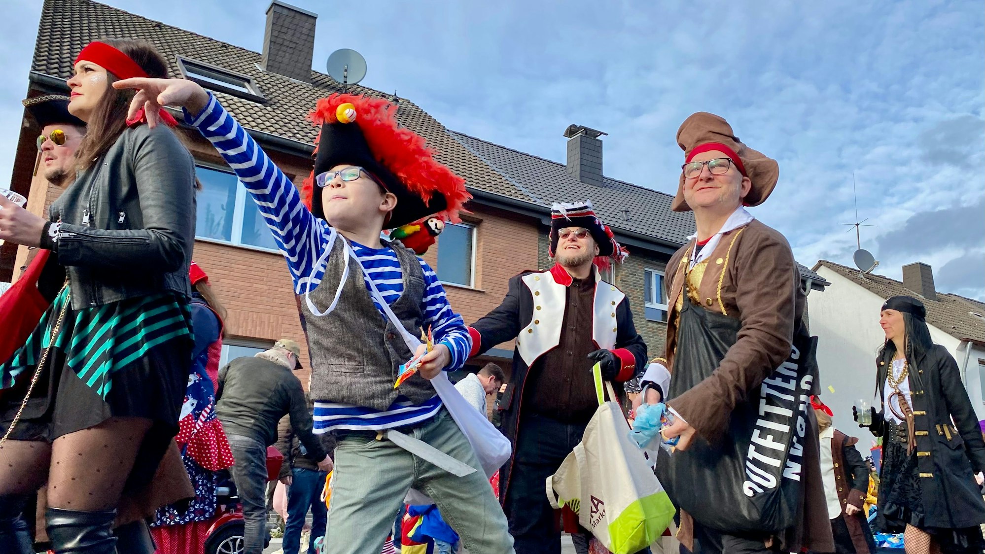 Zu sehen sind kostümierte Menschen, die beim Karnevalszug Süßigkeiten werfen.