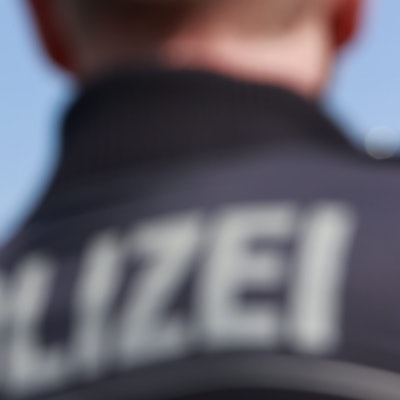 Ein Polizeihubschrauber fliegt am Himmel, im Vordergrund steht ein Polizist.