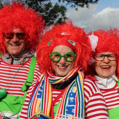 Rote Perücken, rot-weiß-gestreifte Shirts und grellgrüne Latzhosen tragen die drei jecken Handballer.