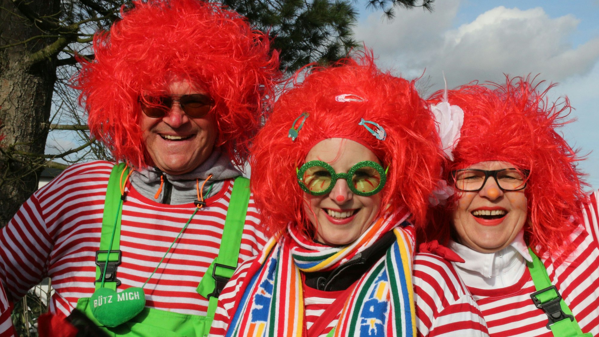 Rote Perücken, rot-weiß-gestreifte Shirts und grellgrüne Latzhosen tragen die drei jecken Handballer.
