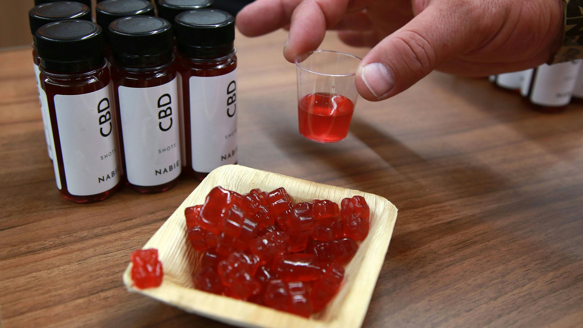 Cannabis-Gummibärchen und CBD-Shots stehen bei einer Hanf-Messe auf einem Tisch. In Russland ist ein Deutscher mit Gummibärchen dieser Art festgenommen worden.