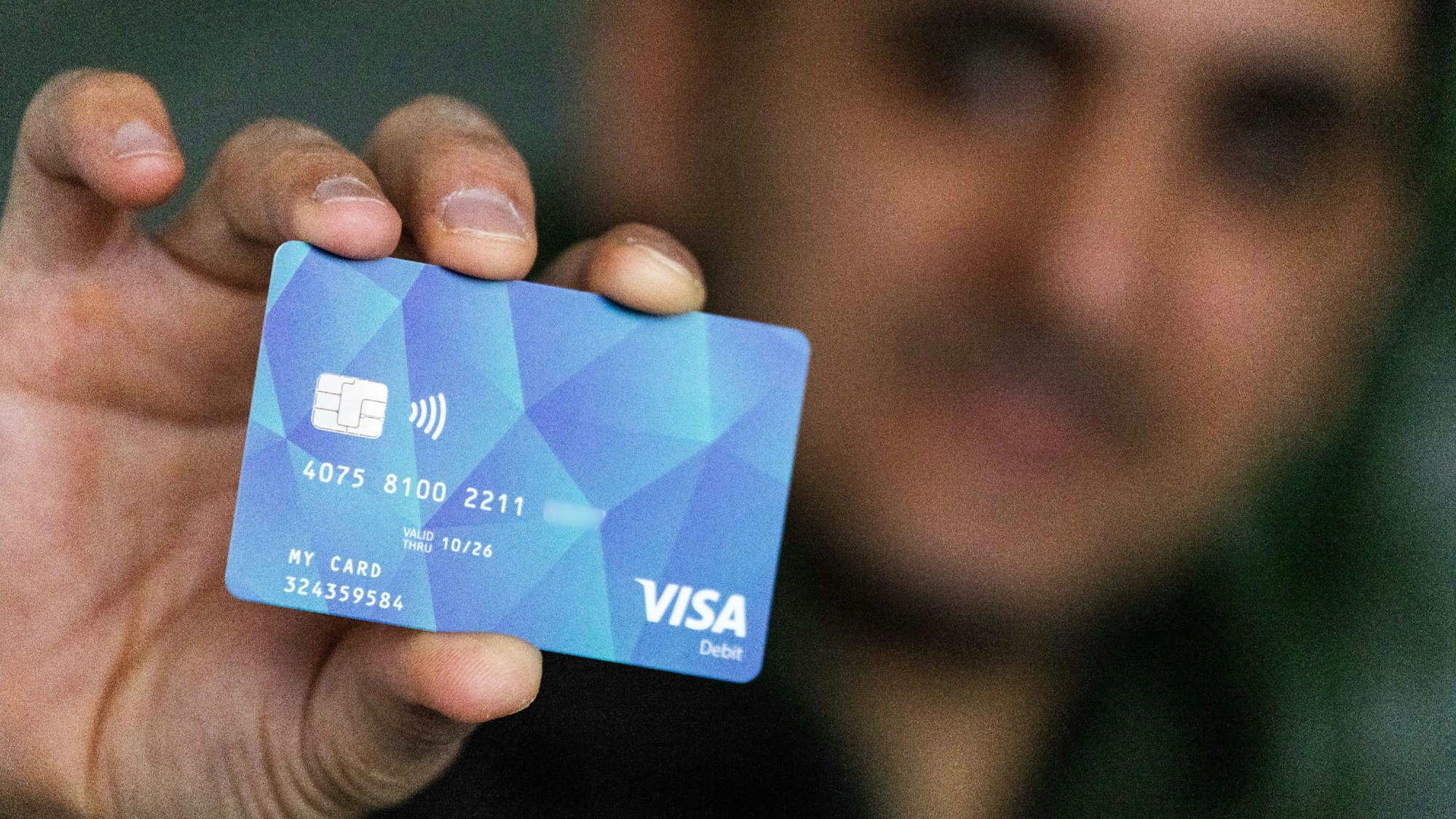 Ein Geflüchteter hält eine Debitcard in der Hand.