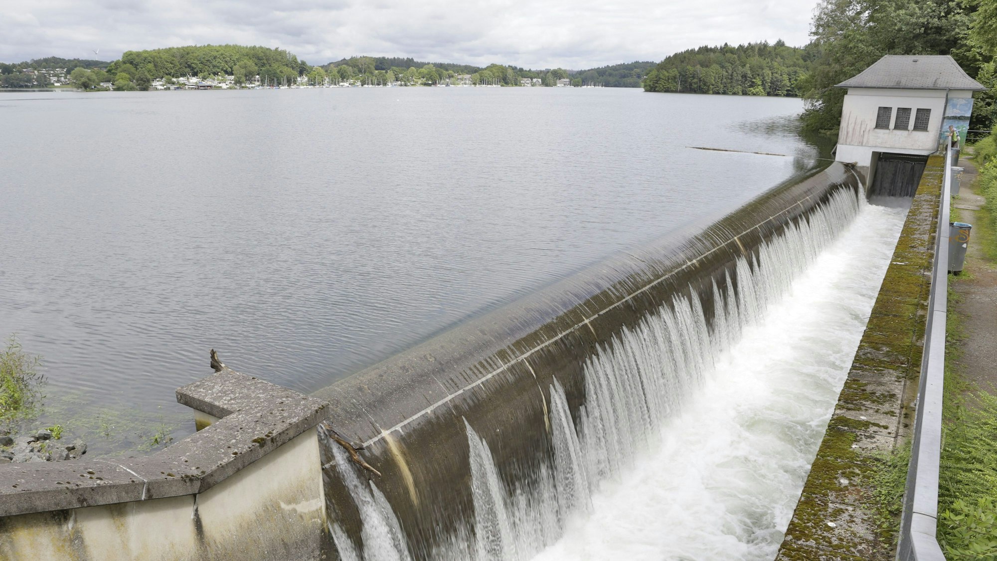 Wasseroberfläche einer Talsperre, Wasser läuft über eine Kante und stürzt in ein kleineres Becken.