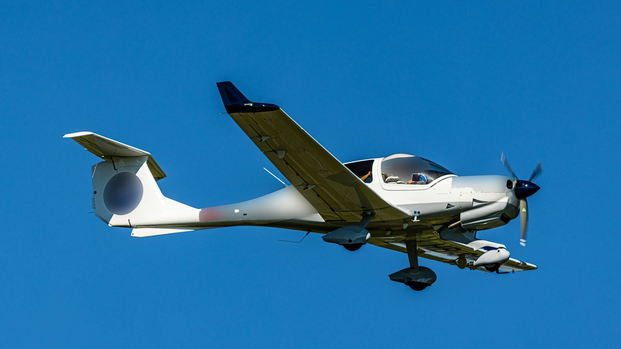 Ein Kleinflugzeug vom Typ Diamond DA40 ist am Himmel unterwegs, im Cockpit sitzt ein Mann mit Sonnenbrille. (Symbolbild)