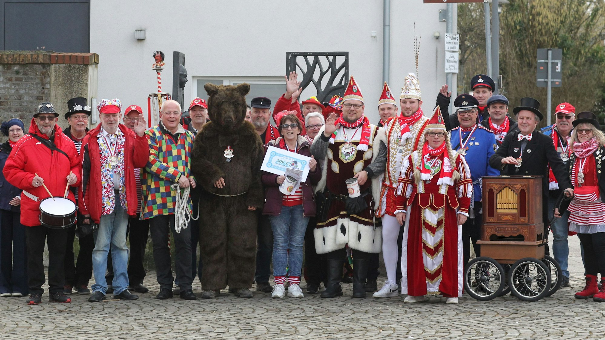 Eine Gruppe von etwa 25 Leuten, darunter der Ääzebär in einem dunkelbraunem Fellkostüm, ein Mann mit Drehorgel, ein Trommler und das Lohmarer Dreigestirn.