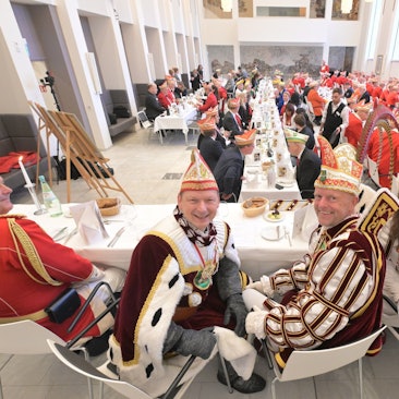 Das Bergisch Gladbacher Dreigestirn sitzt auf dem Podium beim Prinzenessen 2024.