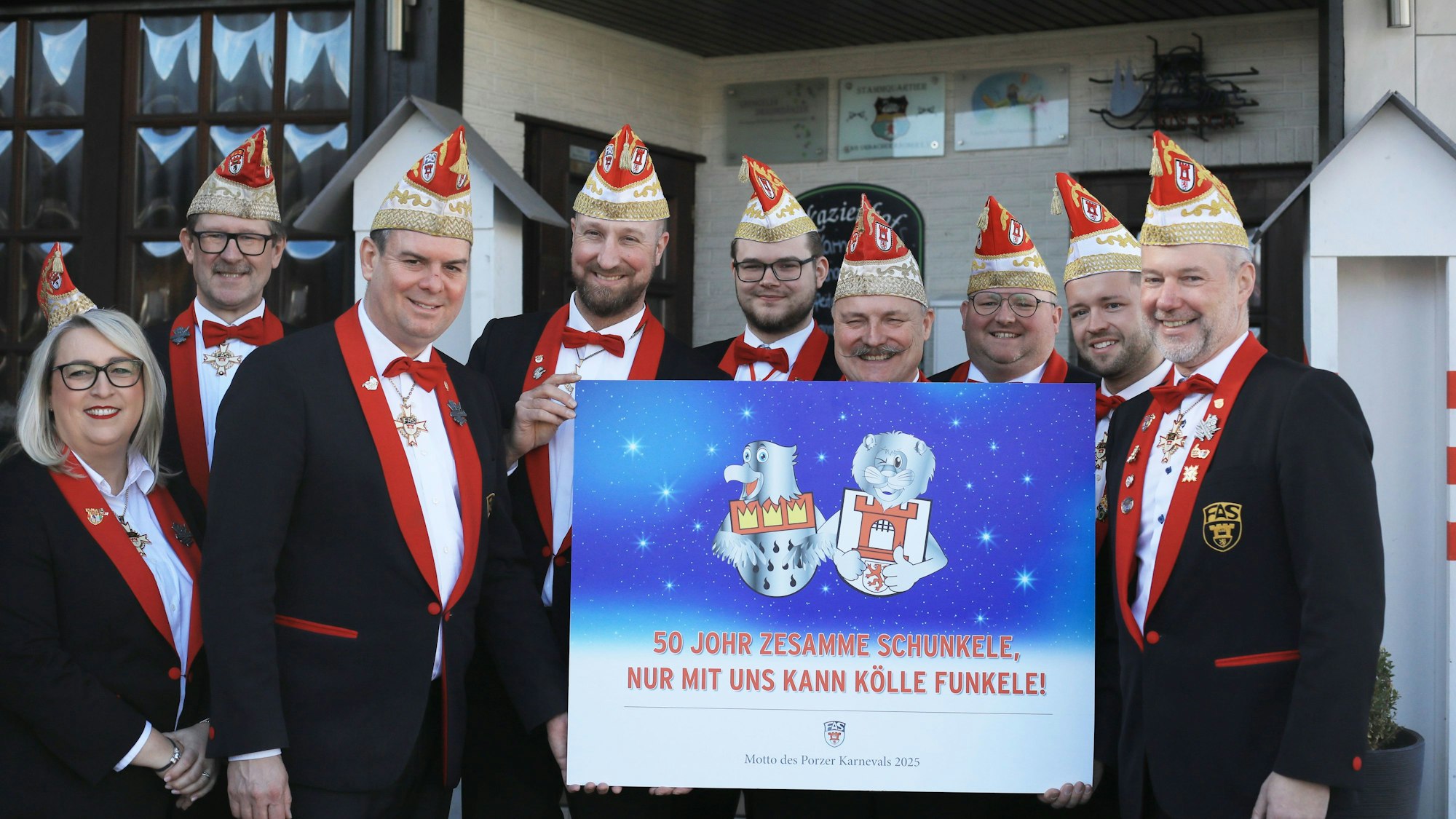 Neun Männer und eine Frau halten ein großes Schild mit dem neuen Sessionsmotto hoch.