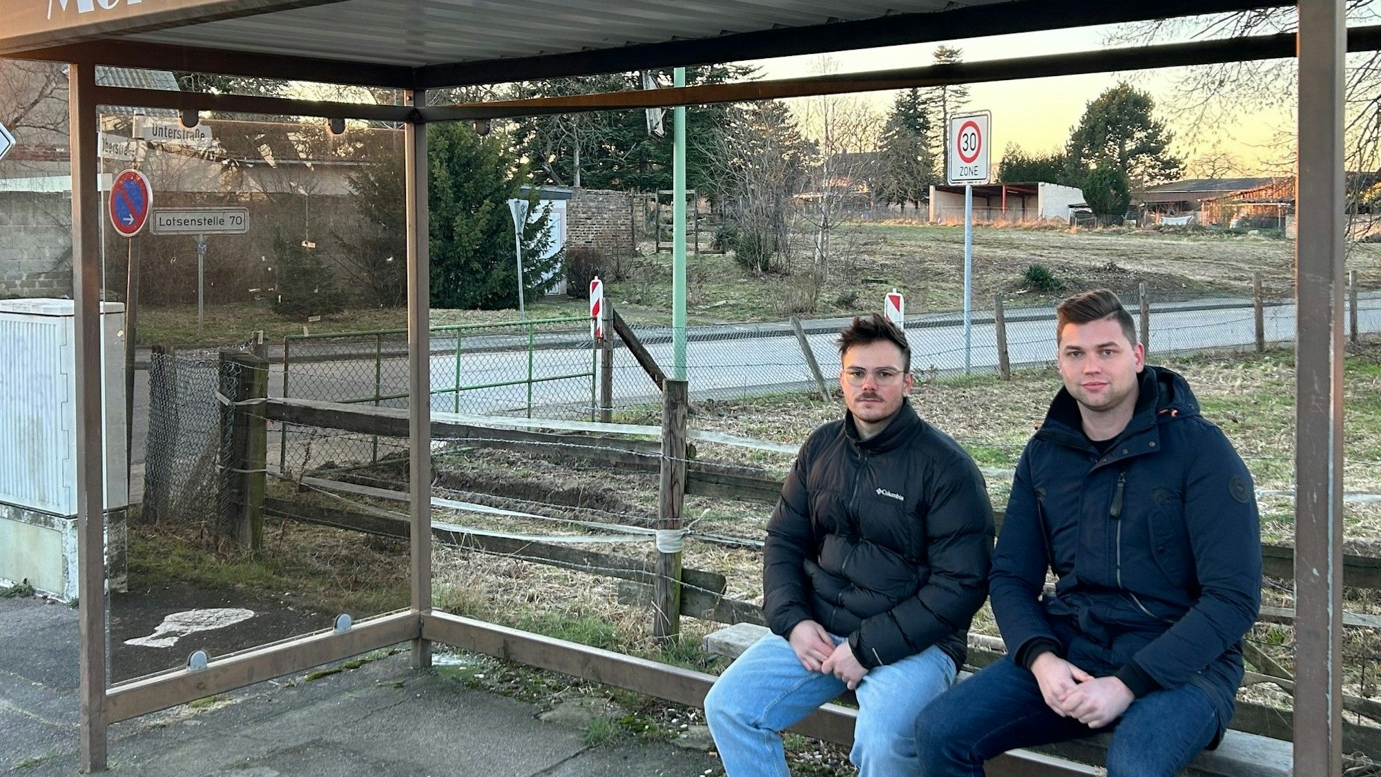Lennart Bongart und Calvin Köcher (v.l.) sitzen im Haltestellenhäuschen von Morschenich. Sie planen, in ihre altes Dorf zurückzukehren, wenn die Bedingungen stimmen.