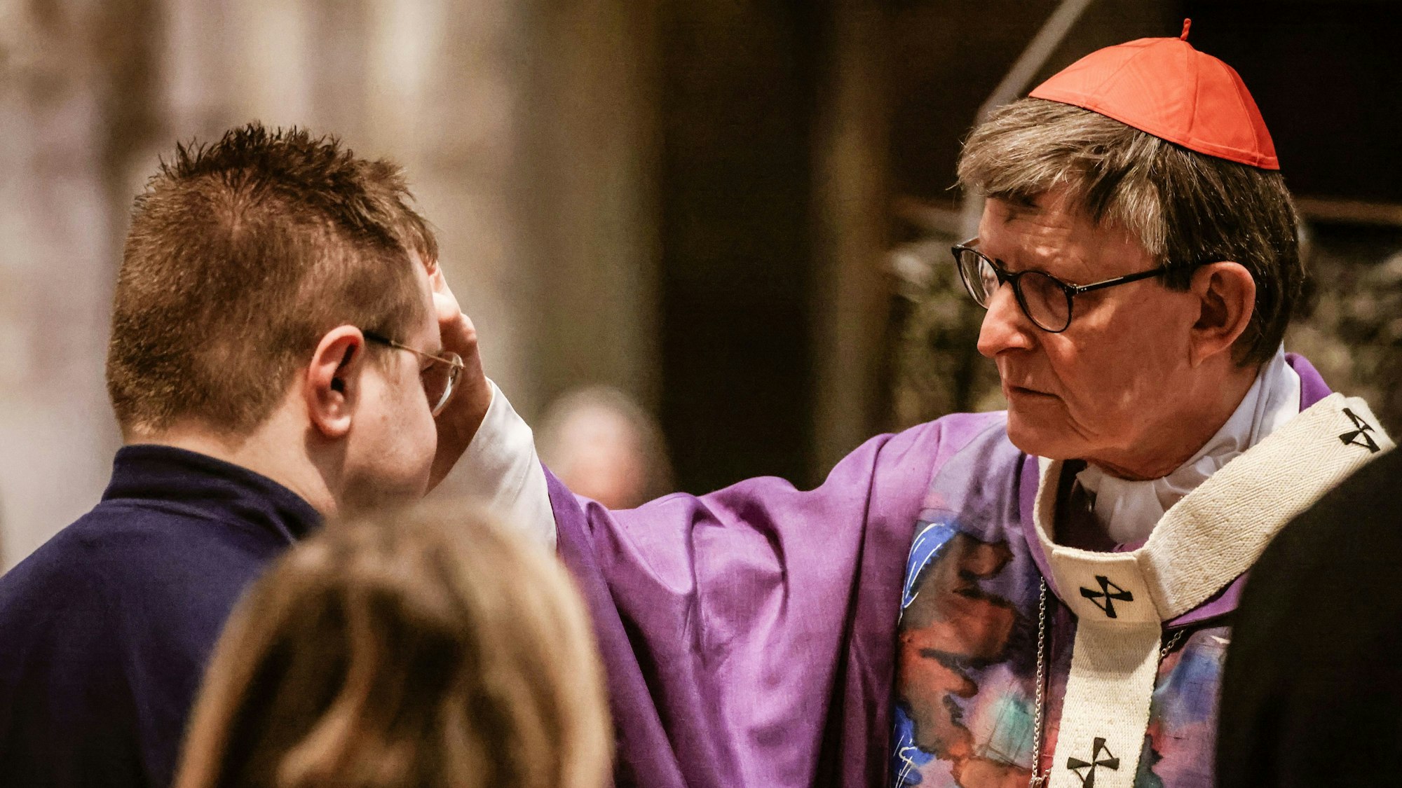 Kardinal Rainer Woelki (rechts) bezeichnet Gläubige im Kölner Dom mit dem traditionellen Aschenkreuz am Beginn der Fastenzeit.