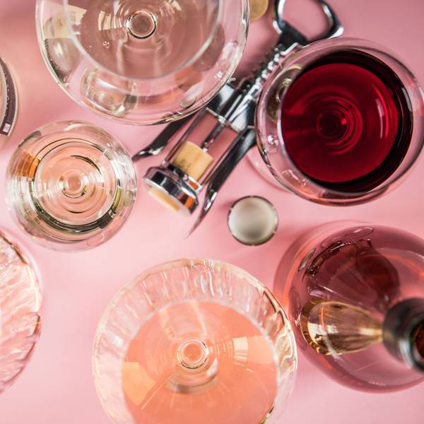 Mehrere Gläser Wein, eine Flasche und ein Korkenzieher liegen auf einer Unterlage.