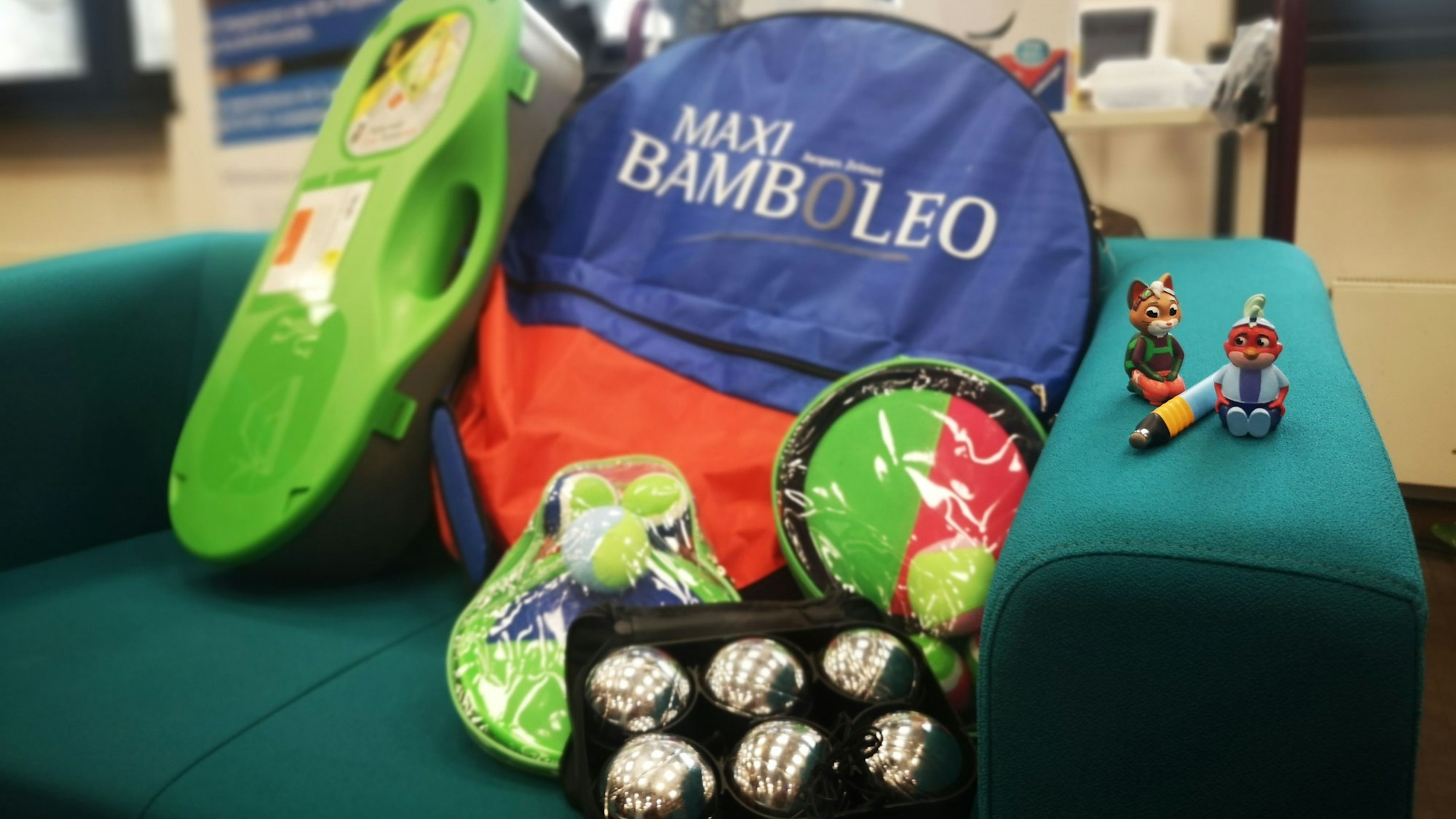 Kleine Spielfiguren, Boccia-Kugeln und weitere bunte Gegenstände liegen auf einem Sessel.