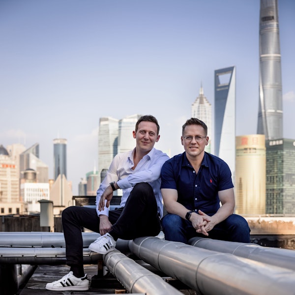 Zwei junge Männer sitzen auf einem Dach nebeneinander.