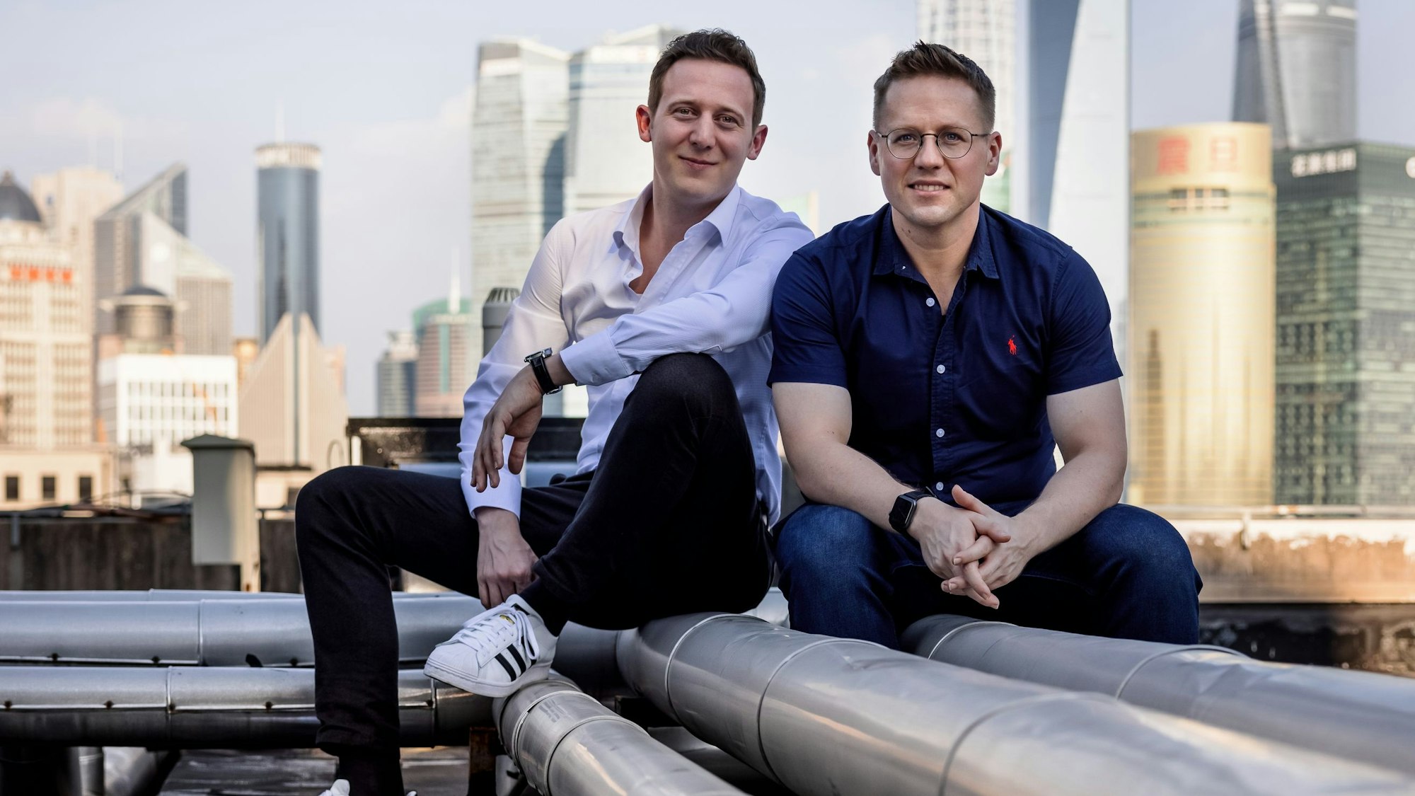 Zwei junge Männer sitzen auf einem Dach nebeneinander.