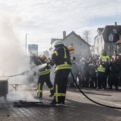 Baden-Württemberg, Biberach an der Riß: Einsatzkräfte der Feuerwehr löschen ein Feuer, das Demonstranten beim politischen Aschermittwoch der baden-württembergischen Grünen vor der Stadthalle von Biberach an der Riß angezündet haben. Die Veranstaltung wurde aufgrund der Proteste vor der Stadthalle abgesagt.