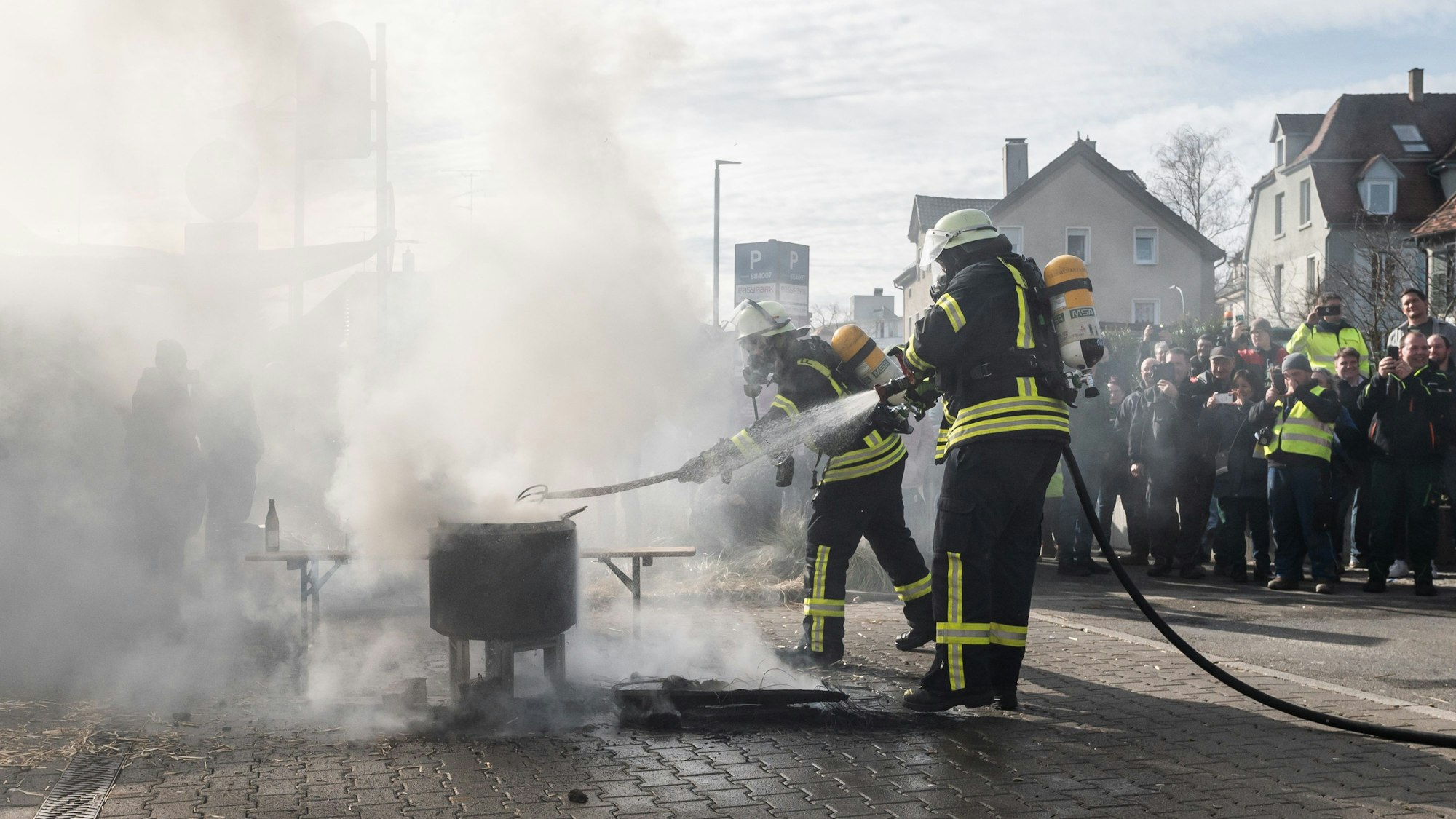 Baden-Württemberg, Biberach an der Riß: Einsatzkräfte der Feuerwehr löschen ein Feuer, das Demonstranten beim politischen Aschermittwoch der baden-württembergischen Grünen vor der Stadthalle von Biberach an der Riß angezündet haben. Die Veranstaltung wurde aufgrund der Proteste vor der Stadthalle abgesagt.